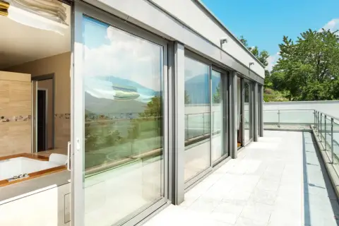 Nowoczesny balkon z przeszklonymi drzwiami i widokiem na góry.